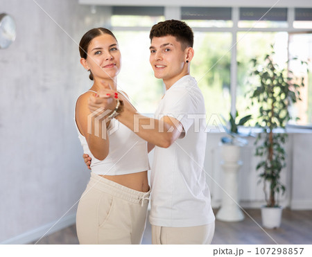 Girls and guys dancing synchronous group choreography in dance hall 107298857