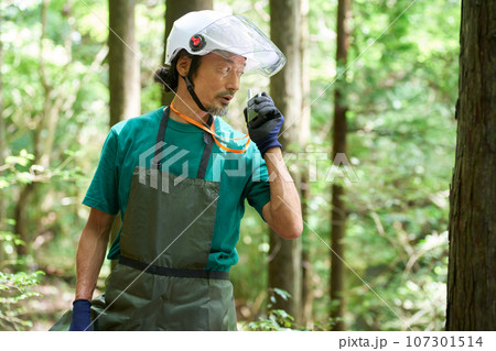 森にてトランシーバーで話すヘルメット着用の男性　森林官　自然保護官　イメージ 107301514