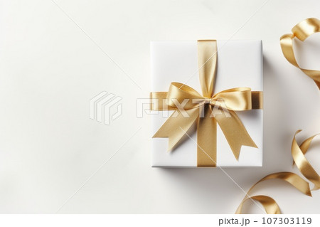 Gift box with golden satin ribbon and bow on white background. Holiday gift with Birthday or Christmas present, top view. Gift box with golden satin ribbon and bow on white background. Holiday gift with Birthday or Christmas present, top view. 107303119