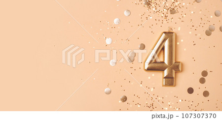 Gold candle in the form of number four on peach background with confetti. 107307370