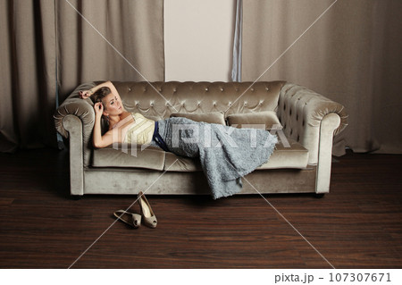 Attractive young model woman lying on sofa indoor 107307671