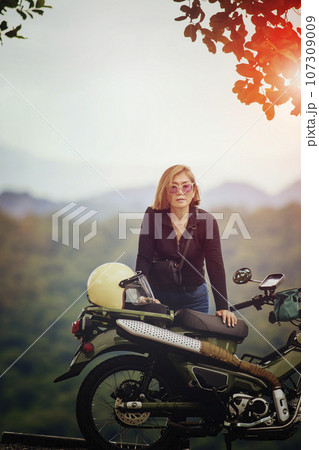 pretty woman standing small enduro motorcycle against beautiful mountain scape at khaoyai national park thailand 107309009