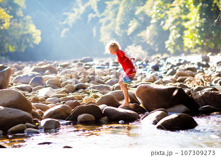 Child hiking in mountains. Kids at river shore. 107309273