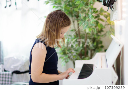 Child playing piano. Kids play music. 107309289
