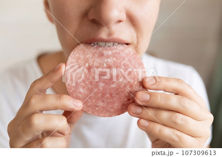 young woman overeats on sausage while dieting young woman overeats on sausage while dieting 107309613
