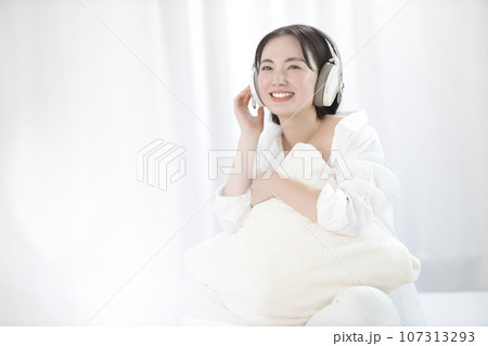 ベッドで音楽を聴いてくつろぐ若い女性 ベッドで音楽を聴いてくつろぐ若い女性 107313293