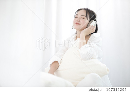 ベッドで音楽を聴いてくつろぐ若い女性 ベッドで音楽を聴いてくつろぐ若い女性 107313295
