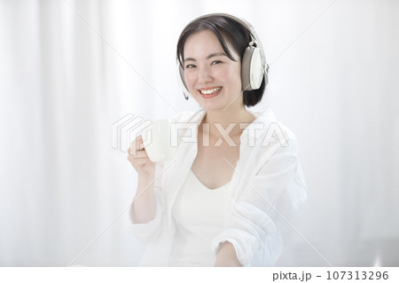 ベッドで音楽を聴いてくつろぐ若い女性 ベッドで音楽を聴いてくつろぐ若い女性 107313296