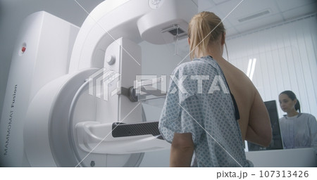 Female doctor adjusts modern mammogram machine for patient 107313426