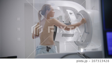 Radiologist pushes button to activate digital mammograph 107313428