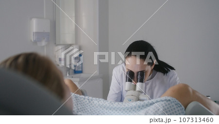 Female gynecologist uses colposcope, takes tests from woman 107313460