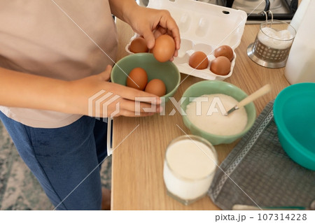 hand pulls out an egg to make scrambled eggs hand pulls out an egg to make scrambled eggs 107314228
