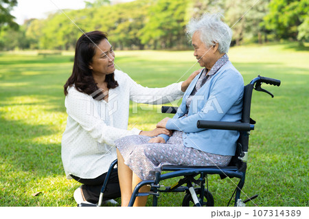 Caregiver help and care Asian elderly woman use walker with strong health while walking at park in happy fresh holiday. Caregiver help and care Asian elderly woman use walker with strong health while walking at park in happy fresh holiday. 107314389