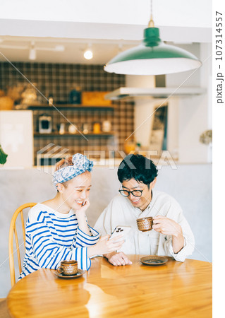 一緒にスマホを見る若い夫婦 カップル 107314557