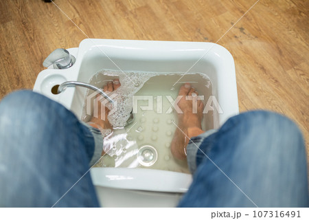 concept of male pedicure, cosmetologist makes classic pedicure for an elderly male client. concept of male pedicure, cosmetologist makes classic pedicure for an elderly male client. 107316491