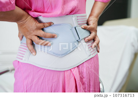 Asian senior wearing elastic support belt can help reduce back pain. 107316713