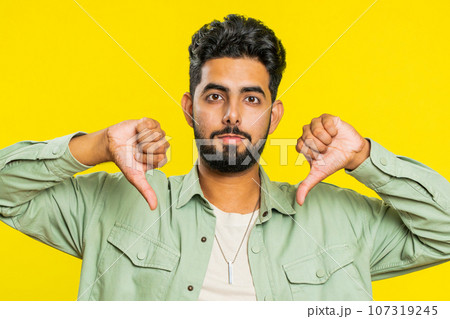 Upset man guy showing thumbs down gesture disapproval dissatisfied dislike negative feedback Upset man guy showing thumbs down gesture disapproval dissatisfied dislike negative feedback 107319245