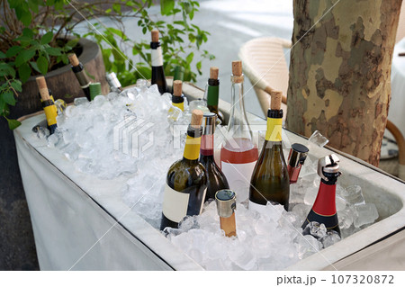 Different wine bottles set in ice bucket on a summer terrace of a restaurant. 107320872