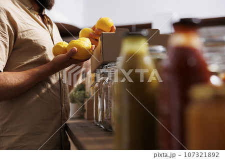 Client purchasing fresh lemons grown by zero waste shop entrepreneur in his garden. Vegan customer happy to find eco friendly preservatives free freshly harvested fruits in local store, close up Client purchasing fresh lemons grown by zero waste shop entrepreneur in his garden. Vegan customer happy to find eco friendly preservatives free freshly harvested fruits in local store, close up 107321892