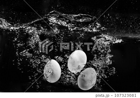 three eggs on black background in water with air bubbles three eggs on black background in water with air bubbles 107323081