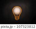 Abstract thinking light bulb on black concrete wall background 107323812