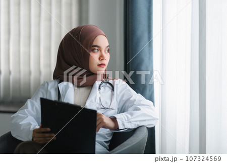 smiling muslim female doctor in brown hijab carrying medical records. smiling muslim female doctor in brown hijab carrying medical records. 107324569