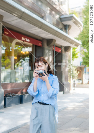 写真を撮影しようとカメラを構えている女性 107325099