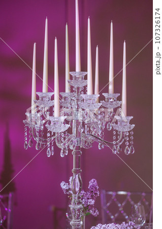 A transparent candelabrum with elegant candles on lavender. 107326174