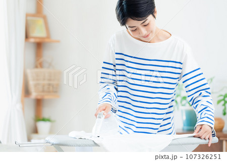 リビングでアイロン掛けする笑顔の女性 リビングでアイロン掛けする笑顔の女性 107326251