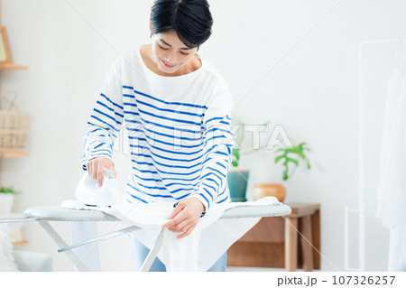 リビングでアイロン掛けする笑顔の女性 107326257
