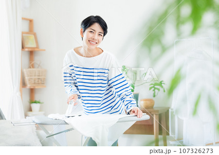リビングでアイロン掛けする笑顔の女性 リビングでアイロン掛けする笑顔の女性 107326273