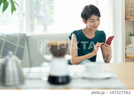リビングでスマートフォンを操作する女性 リビングでスマートフォンを操作する女性 107327562