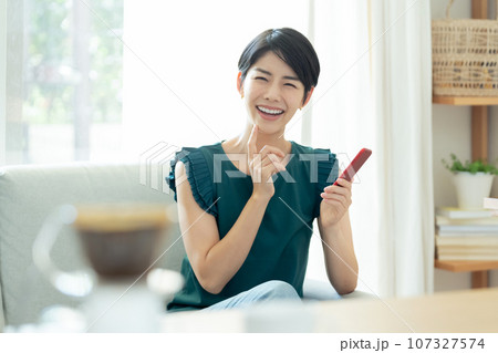 リビングでスマートフォンを操作する女性 リビングでスマートフォンを操作する女性 107327574