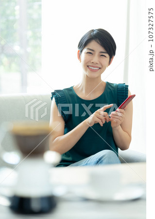 リビングでスマートフォンを操作する女性 107327575