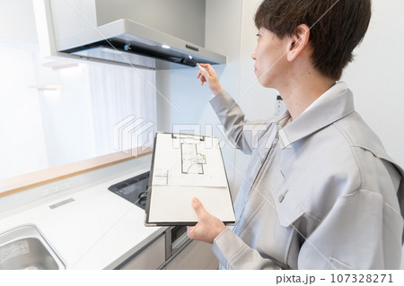 図面を見ながらキッチンのリフォームを打ち合わせする作業服の男性 107328271