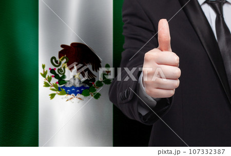 Mexican concept. Businessman showing thumb up on the background of flag of Mexico 107332387