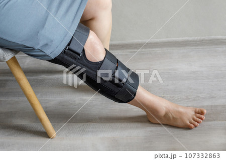 Female leg after knee surgery in bandages and orthosis, closeup 107332863
