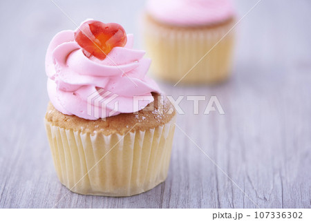 Two cupcakes on wooden background Two cupcakes on wooden background 107336302