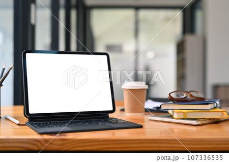 Digital tablet, books, glasses and paper cup of coffee on wooden office table 107336535