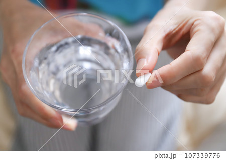 薬を飲む手元 107339776