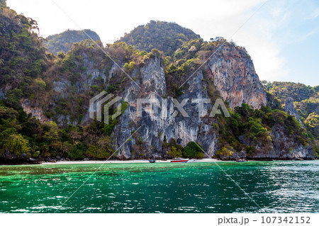 A picturesque beautiful place on the island of Phi Phi Leh - Pi Leh Lagoon is popular for excursions with tourists on traditional Thai fishing boats. Island travel in Thailand. A picturesque beautiful place on the island of Phi Phi Leh - Pi Leh Lagoon is popular for excursions with tourists on traditional Thai fishing boats. Island travel in Thailand. 107342152