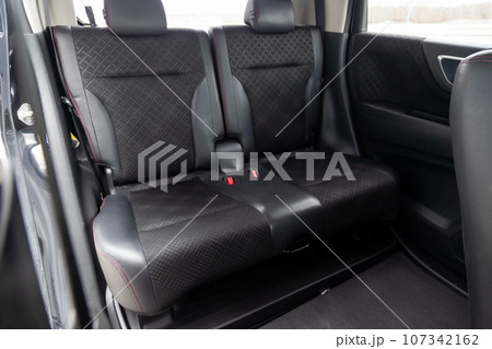 Close-up on rear seats with velours fabric upholstery in the interior of an modern japanese car in gray after dry cleaning. Auto service industry. 107342162