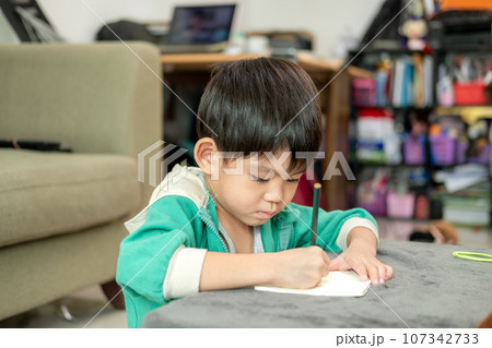 A boy is drawing pictures on a notebook on the table. Learning outside the classroom A boy is drawing pictures on a notebook on the table. Learning outside the classroom 107342733