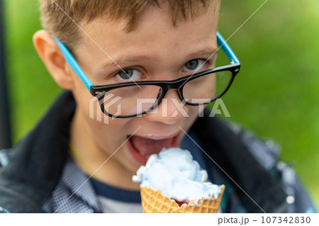 boy eats ice cream in a waffle cone on the street in the park 107342830