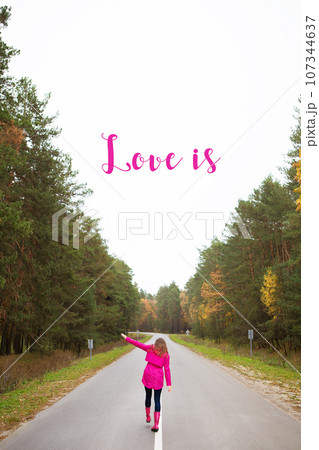 a girl in a pink raincoat and in rubber boots walks on the road in the middle of the forest-inscription love is a girl in a pink raincoat and in rubber boots walks on the road in the middle of the forest-inscription love is 107344637