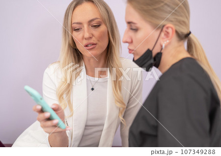 A woman shows the desired result to the master on a smartphone. A woman shows the desired result to the master on a smartphone. 107349288