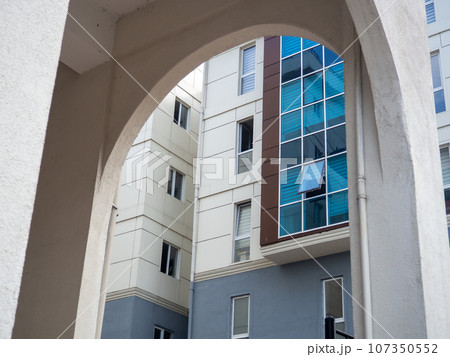 Arch and glazed windows. Modern urban architecture. High building from an unusual angle Arch and glazed windows. Modern urban architecture. High building from an unusual angle 107350552