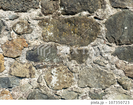 Remains of an old castle. Ancient fortifications made of stone. Museum in the open air. Wall of a medieval castle. Background from ancient stonework. Remains of an old castle. Ancient fortifications made of stone. Museum in the open air. Wall of a medieval castle. Background from ancient stonework. 107350723