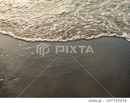 Wet sand of the beach in the rays of the setting sun. The silence of the wild beach. Natural background. Black sand in the sun close-up. Quiet place. Edge of the coast. Bathing place. Wet sand of the beach in the rays of the setting sun. The silence of the wild beach. Natural background. Black sand in the sun close-up. Quiet place. Edge of the coast. Bathing place. 107350858