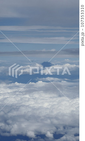 飛行機の窓から見た、雲に一部隠れた遠景の富士山 飛行機の窓から見た、雲に一部隠れた遠景の富士山 107353310